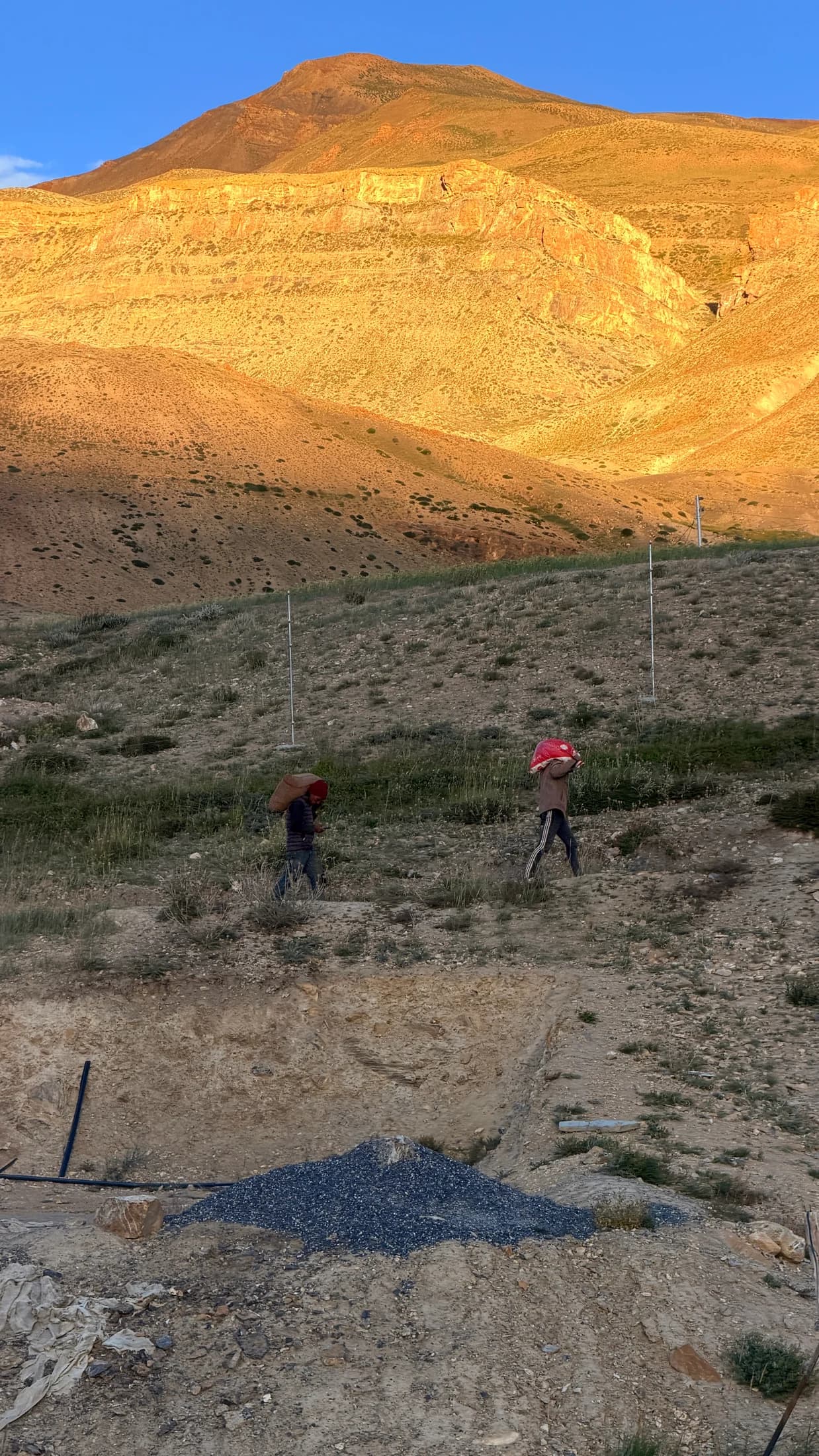 People walking beneath golden mountain slopes